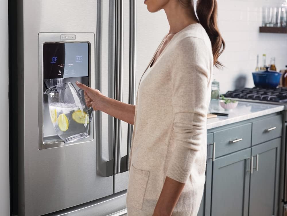 Person using a refrigerator's water dispenser with a glass containing lemon slices.